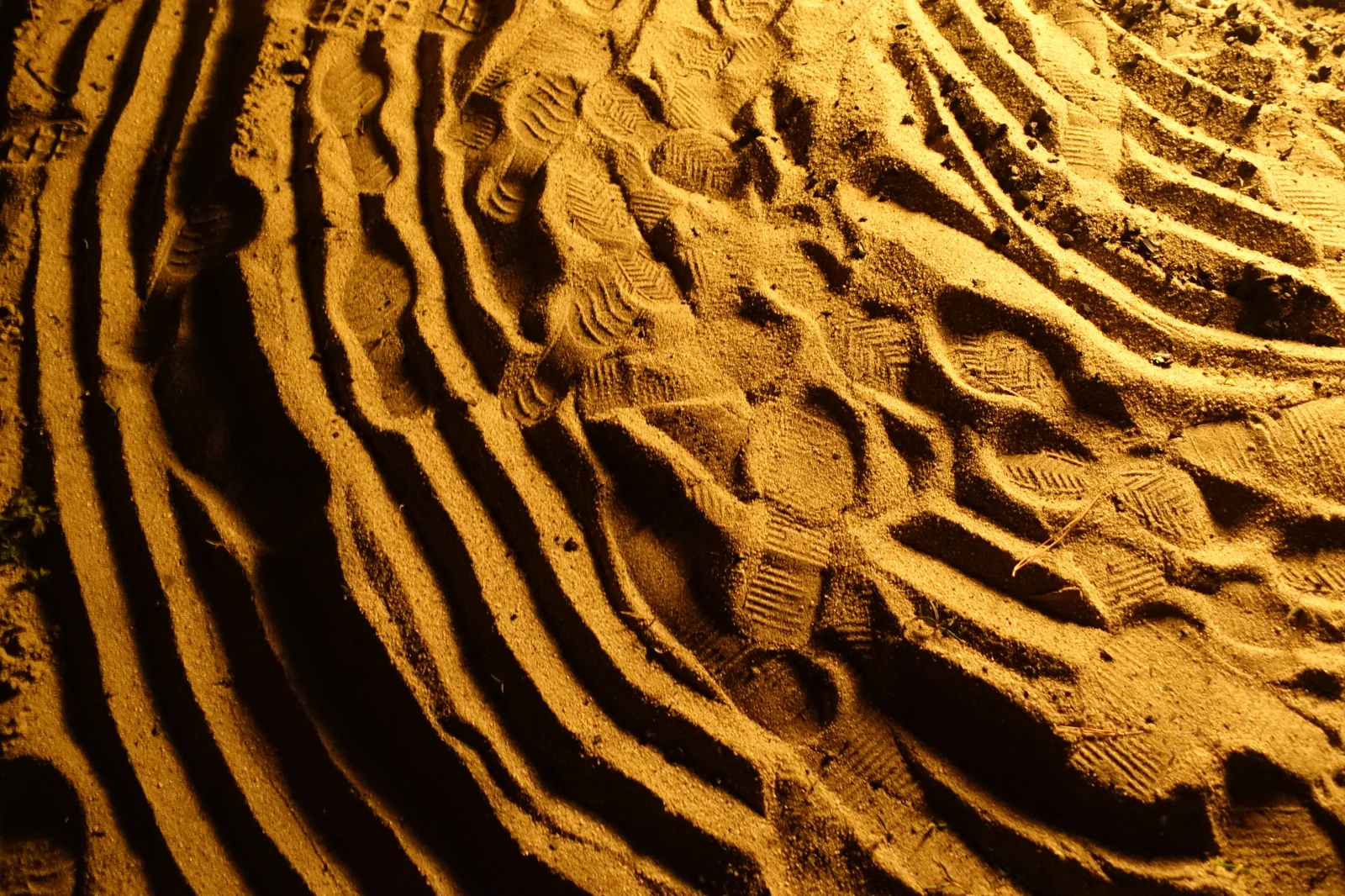 Patterns of footprints and tracks in warm-toned sand