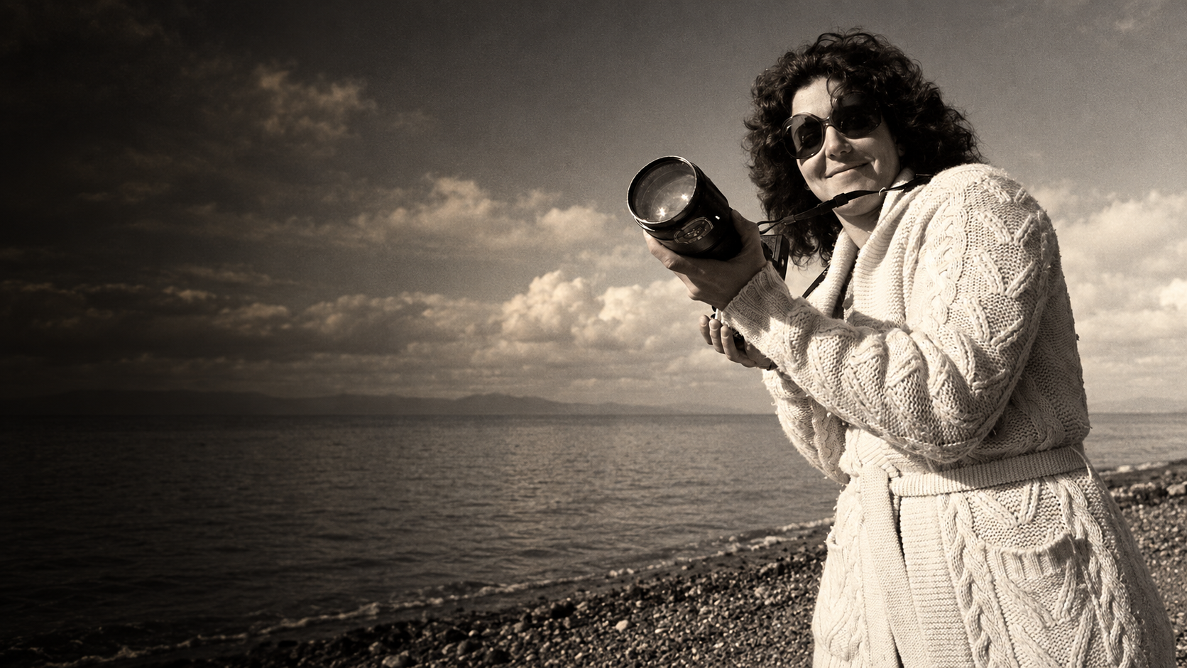 Vintage portrait of Caris Palm Turpen holding a camera beside the sea.